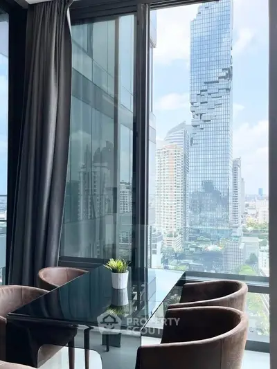 Stunning city view from modern high-rise apartment with sleek glass dining table and plush chairs.