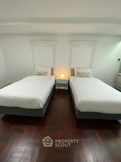 Spacious bedroom with twin beds and elegant wooden flooring