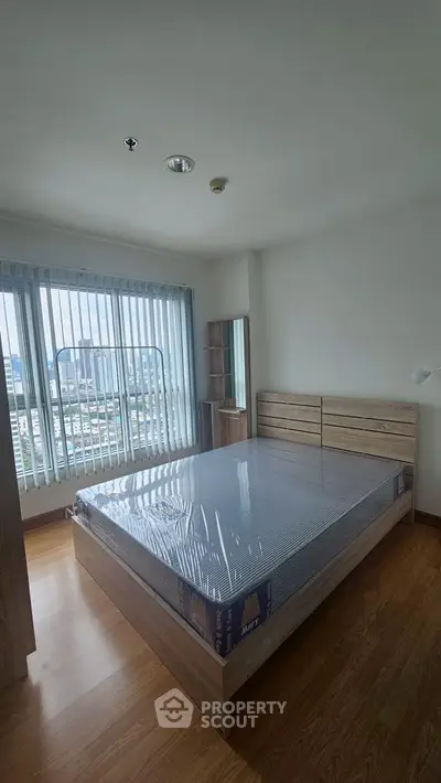 Spacious bedroom with large window and wooden flooring in modern apartment