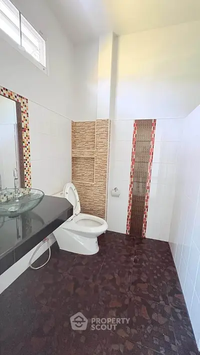 Modern bathroom with stylish glass sink and tiled walls