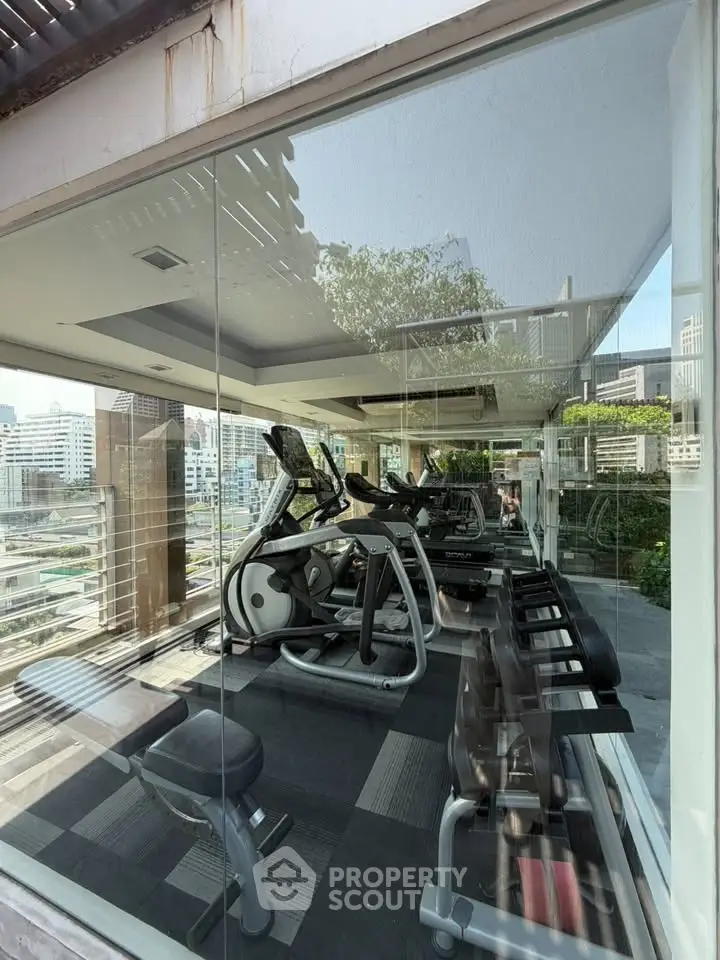 Modern gym with city view, featuring state-of-the-art fitness equipment and sleek design for an upscale workout experience.