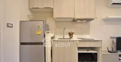 Modern compact kitchen with fridge, microwave, and sleek cabinetry