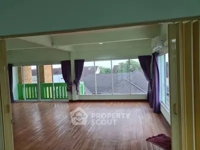 Spacious living room with large windows and wooden flooring, offering a bright and airy atmosphere.