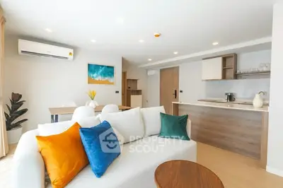 Modern open-layout living room with vibrant cushions and sleek kitchen area