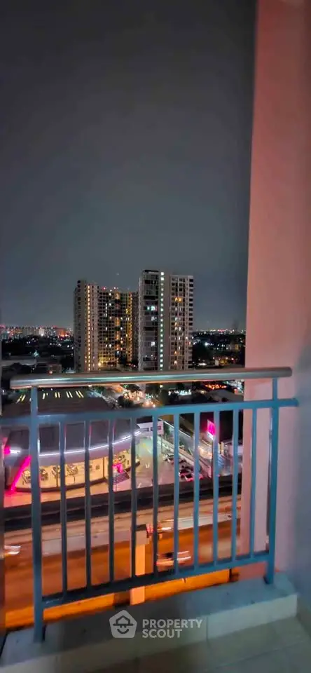 Stunning night view from a balcony overlooking cityscape with illuminated buildings.