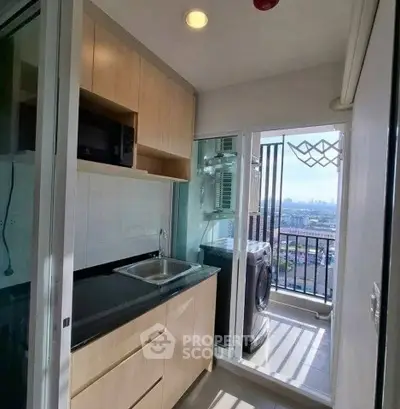 Compact kitchen with balcony view and modern appliances in urban apartment