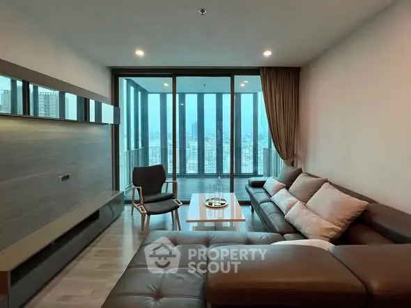 Modern living room with large windows and city view, featuring a stylish sectional sofa and elegant decor.