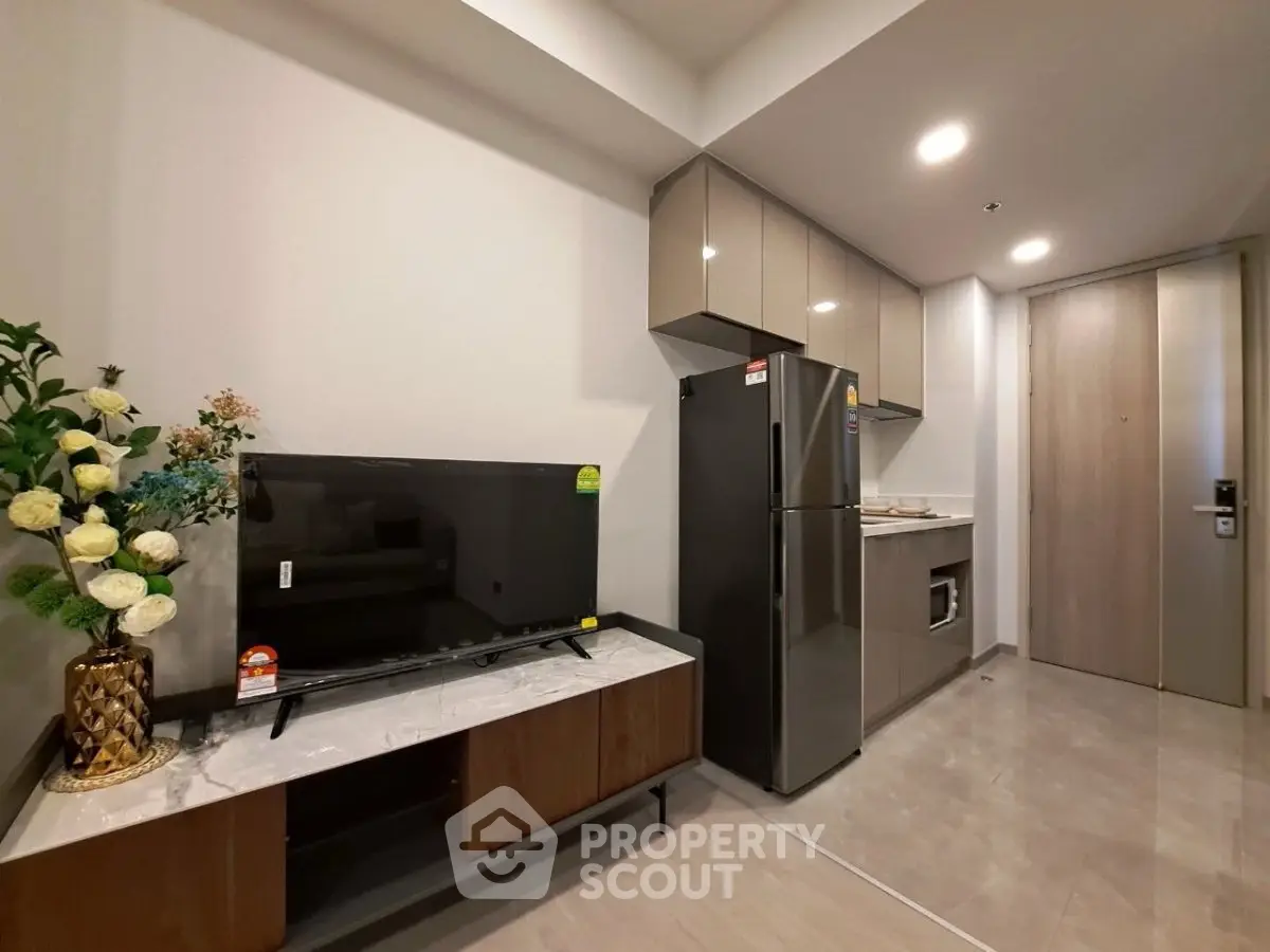 Modern kitchen with sleek cabinets, stainless steel fridge, and elegant decor in a stylish apartment.