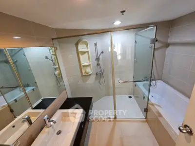 Modern bathroom with glass shower and bathtub, dual sinks, and elegant tile design.