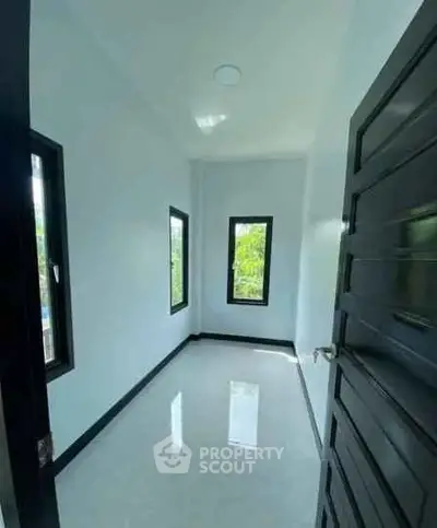 Bright and airy small room with large windows and sleek black door, perfect for a cozy study or office space.