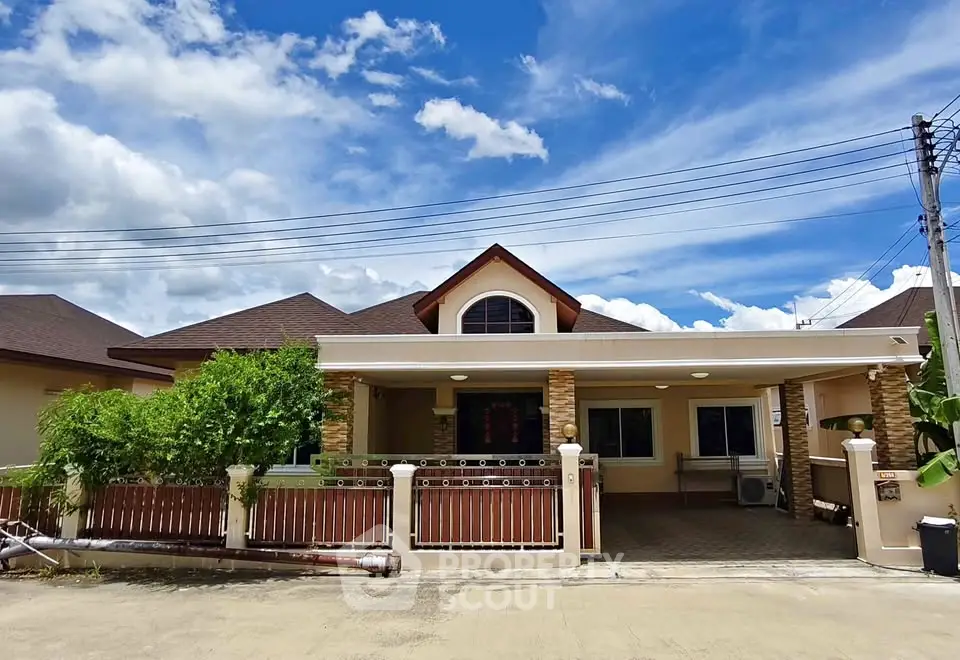 Charming single-story home with a spacious driveway and lush greenery under a bright blue sky.