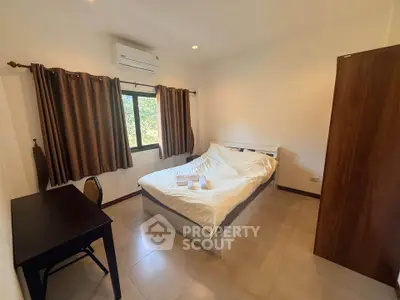 Cozy bedroom with natural light, featuring a bed, desk, and air conditioning, ideal for comfortable living.