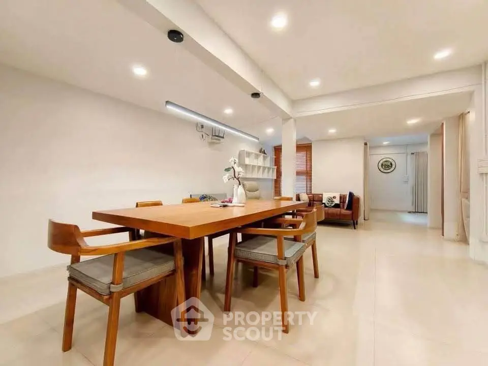 Spacious modern dining area with wooden table and chairs, open layout, and cozy living room view.