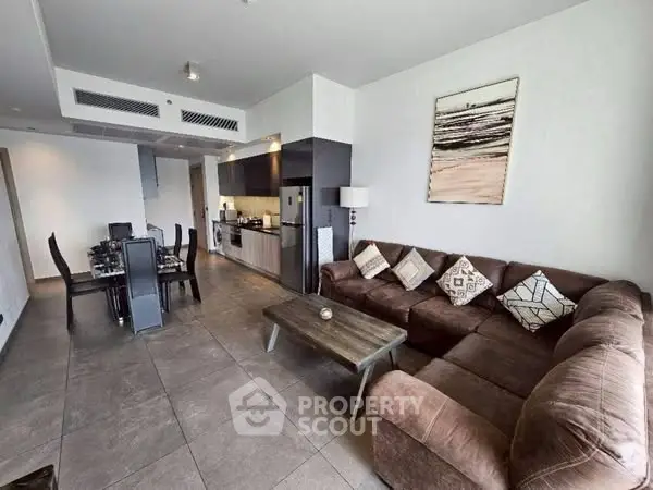 Spacious modern living room with open kitchen and dining area, featuring stylish decor and ample seating.