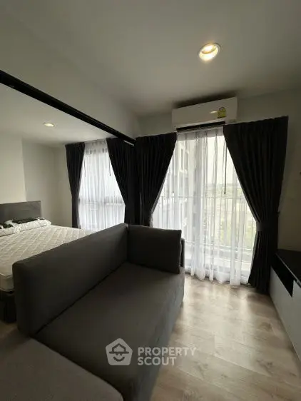 Modern bedroom with cozy sofa and large windows for natural light