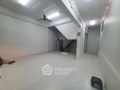 Spacious open-plan interior with staircase and ceiling fan, ideal for versatile use.