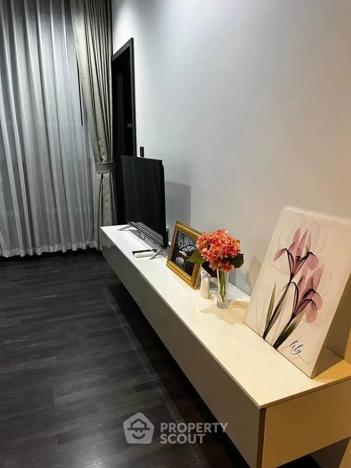 Modern living room with sleek TV stand, elegant decor, and dark wood flooring.