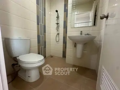Modern bathroom with sleek fixtures and neutral tiles, featuring a shower and toilet.