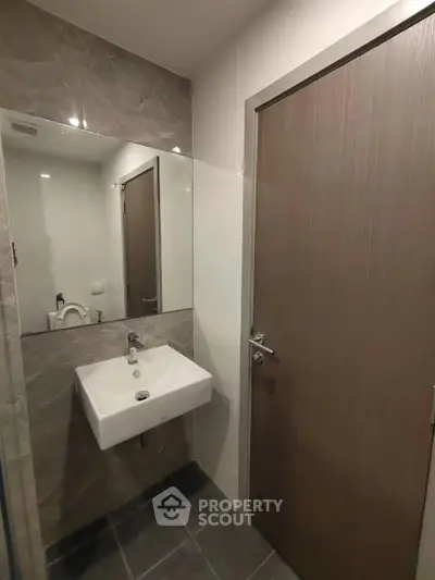 Modern bathroom with sleek sink and large mirror in contemporary apartment.