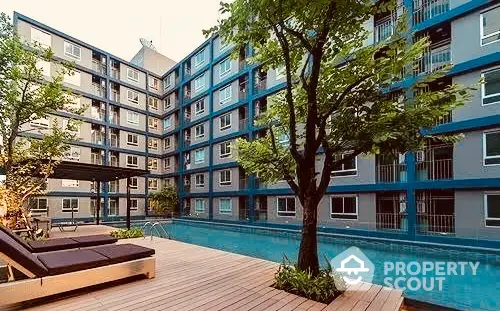 Inviting modern apartment complex with a sparkling pool, surrounded by lush greenery and stylish lounging areas, perfect for urban living.