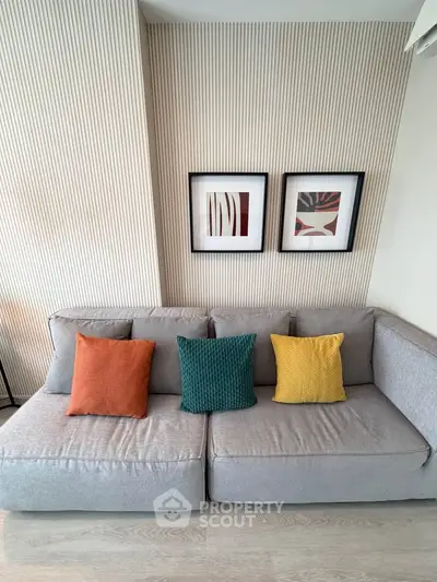 Modern living room with stylish sofa and colorful cushions, featuring contemporary wall art and elegant decor.