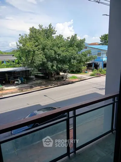 Charming balcony view overlooking a quiet street and lush greenery, perfect for relaxation.