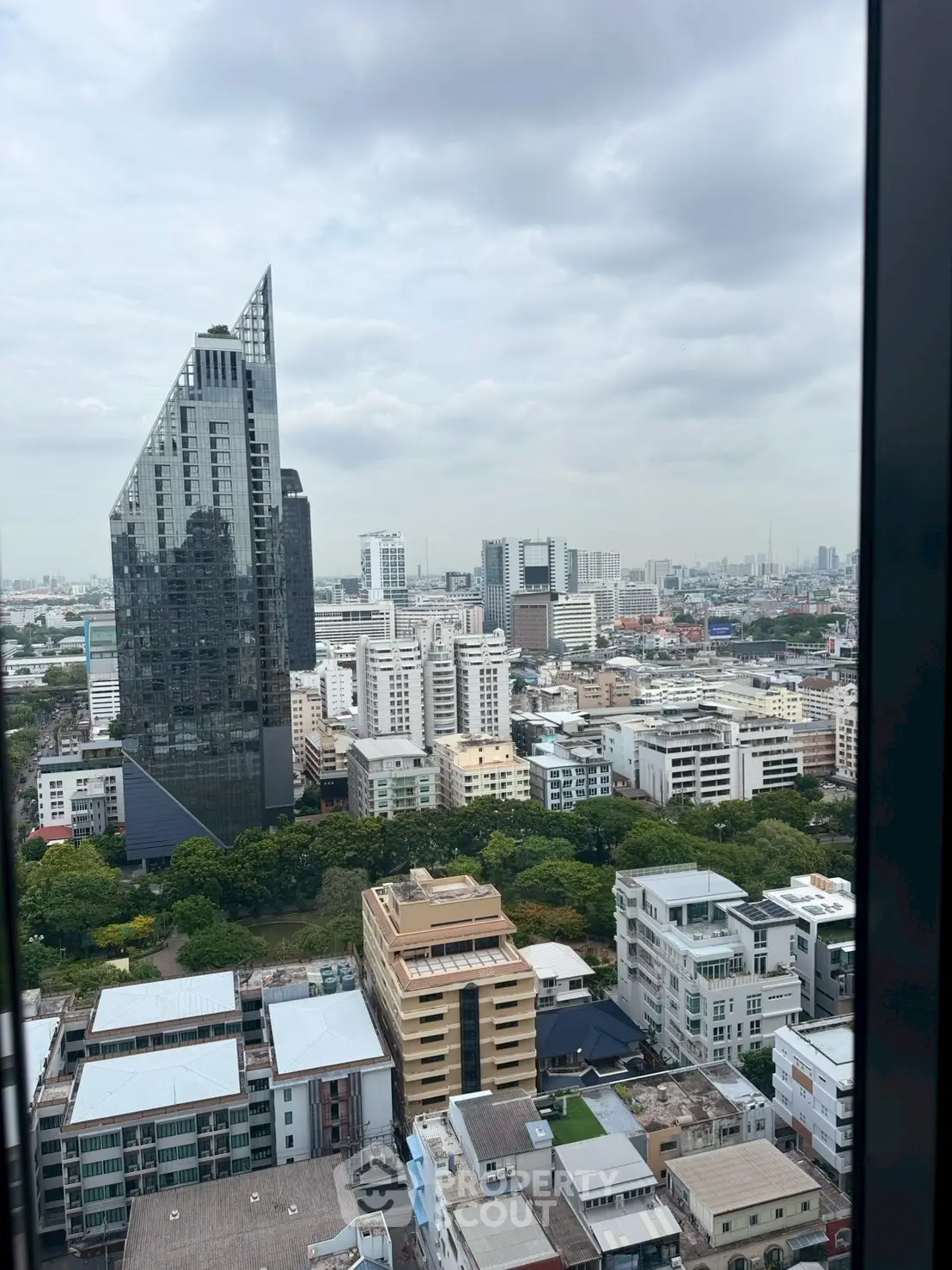 Stunning cityscape view from a high-rise building, showcasing modern architecture and lush greenery.