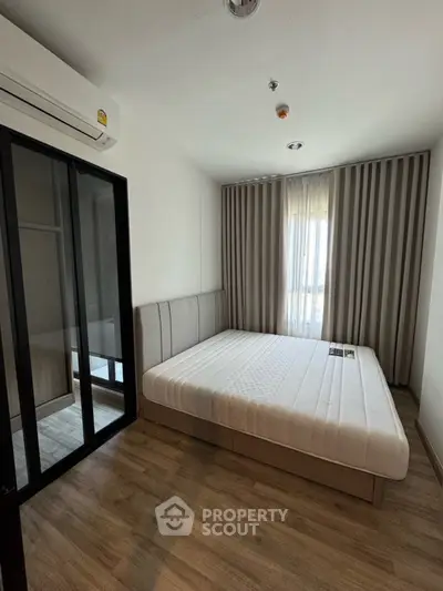 Modern bedroom with large window and stylish decor in a contemporary apartment.