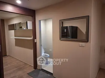 Modern apartment interior with wooden flooring and a compact bathroom.
