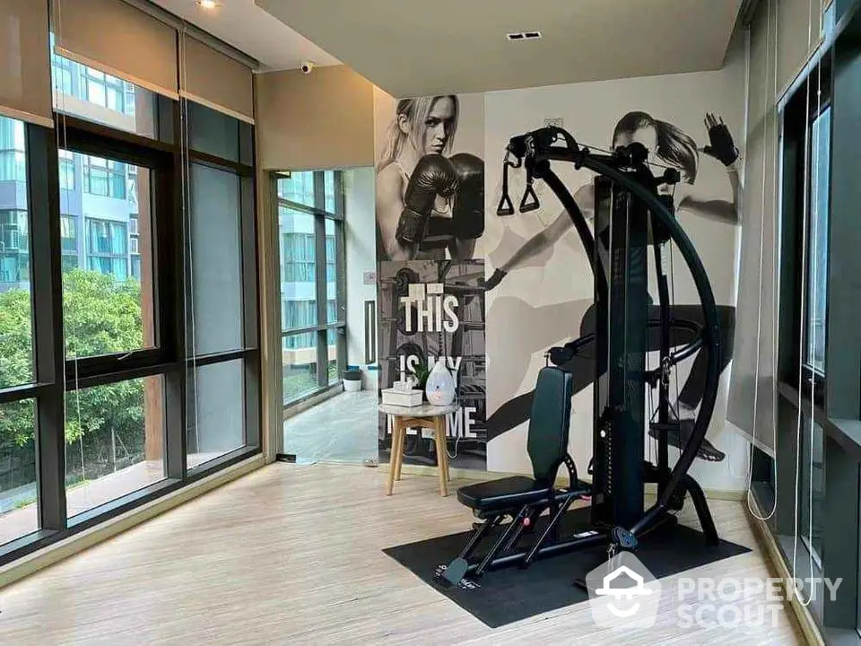 Modern gym room with exercise equipment and large windows in luxury apartment building.