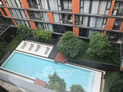 Modern apartment building with a luxurious swimming pool and lush greenery view.