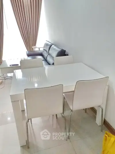 Modern living room with sleek white dining table and elegant leather sofa.