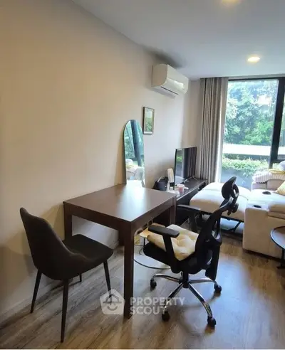 Modern living room with stylish furniture and large window offering lush garden view.