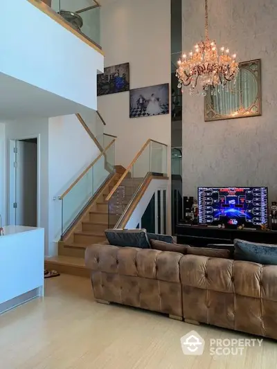 Luxurious living room with elegant chandelier and modern staircase in a stylish duplex apartment.