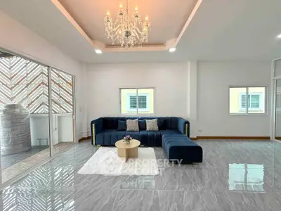 Spacious modern living room with elegant chandelier and stylish blue sofa.