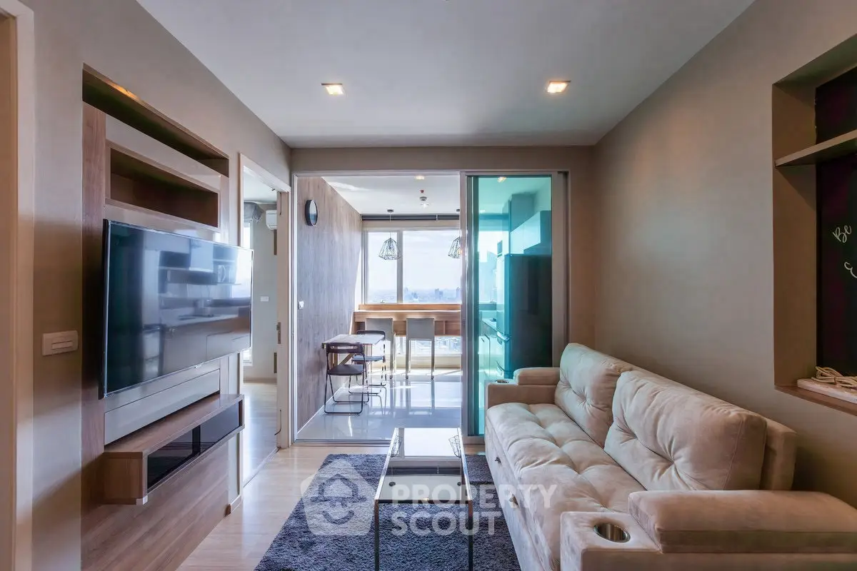 Modern living room with sleek design and large TV, leading to a bright balcony with a view.