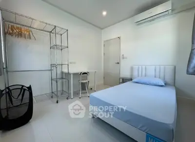 Minimalist bedroom with single bed, desk, and open closet in bright modern apartment.