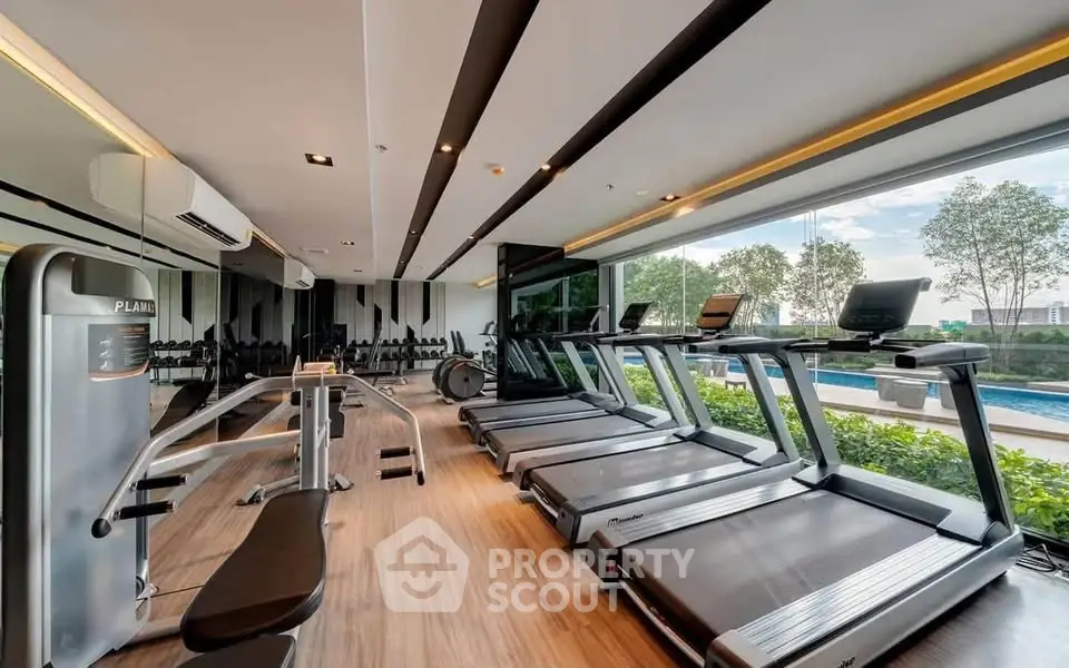 Modern gym with state-of-the-art equipment and pool view in luxury residential complex.