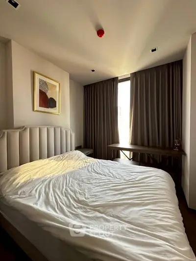 Cozy bedroom with modern decor and natural light, featuring a plush bed and elegant curtains.
