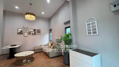 Modern living room with elegant decor, featuring a stylish chandelier, cozy sofa, and contemporary wall art.