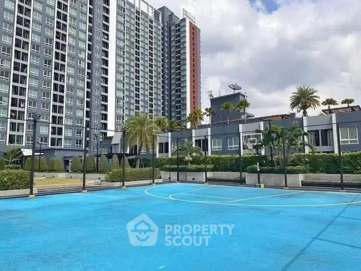 Modern high-rise building with outdoor sports court and lush landscaping.