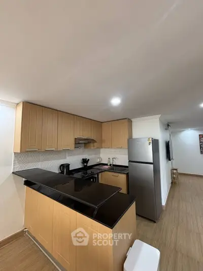 Modern kitchen with sleek wooden cabinets and black countertops in a stylish apartment.