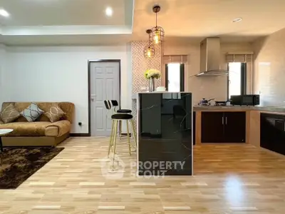 Modern open-layout kitchen and living room with stylish decor and cozy seating area.
