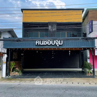 Modern commercial building with sleek facade and ample parking space in vibrant neighborhood.