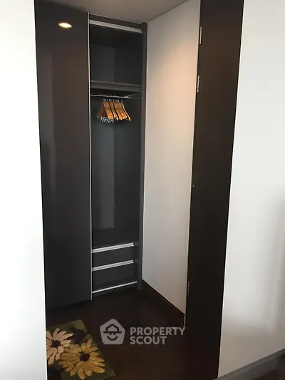 Modern walk-in closet with sleek dark wood finish and ample storage space.