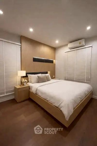 Modern bedroom with cozy lighting and elegant wooden flooring, featuring a comfortable bed and stylish decor.