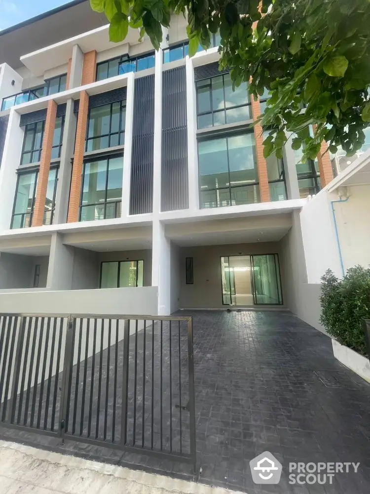 Modern multi-story building with large windows and gated driveway