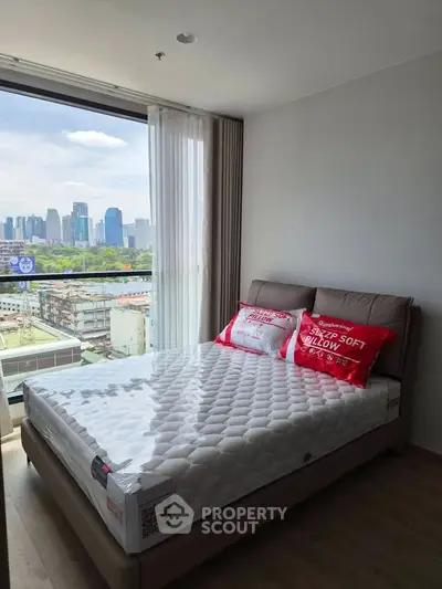 Modern bedroom with city view, featuring a cozy bed and large window overlooking skyline.