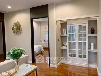 Elegant living room with wooden floors and stylish decor leading to a cozy bedroom.