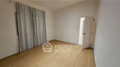 Spacious empty room with wooden flooring and curtain, ready for customization.